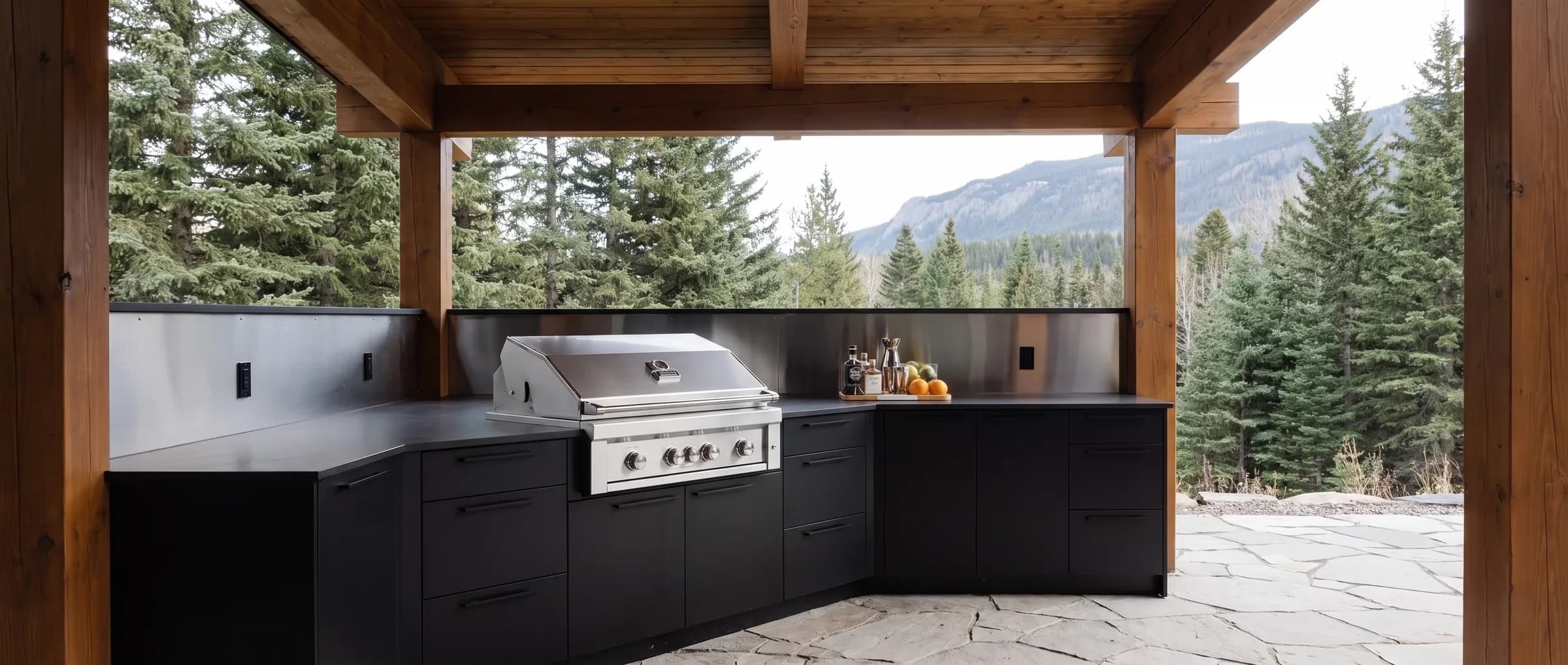 Built-in stainless grill in a matte black island under a covered timber structure